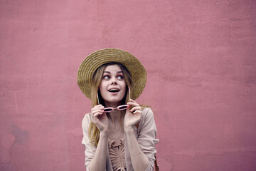 emotional woman in hat walking in the city open air against pink wall background