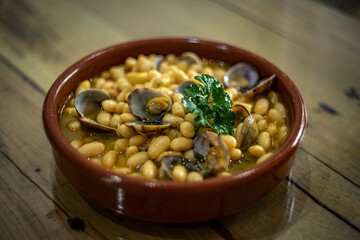 Fabada comida tradicional asturiana con almejas en plato de barro