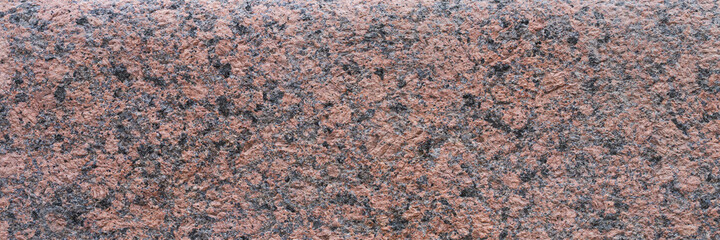 Granite texture. Natural pink granite with a grainy pattern. Stone background. Solid rough surface of rock. Durable construction and decoration material. Close-up.