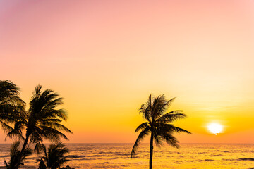 Obraz na płótnie Canvas Beautiful tropical beach sea ocean at sunrise or sunset with palm tree