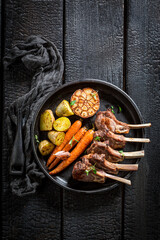 Top view of roasted lamb ribs with vegetables and thyme