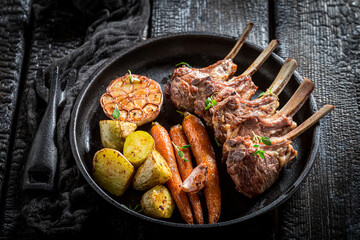 Roasted ribs of lamb with vegetables on black table