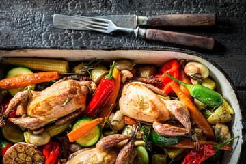 Homemade roasted quails with vegetables in casserole