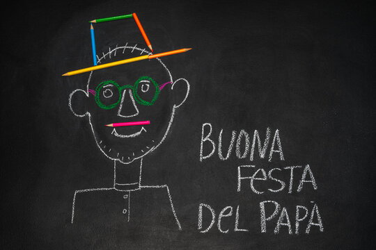 Inscription in Italian Happy Fathers Day. childrens picture of happy daddy made with chalk on blackboard