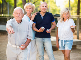 Glad cheerful positive family playing petanque in outdoor
