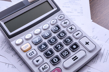 Calculator keypad with checks from the store from shopping on a wooden floor background. Top view. Copy space