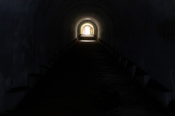A sunlit exit from a dark dungeon. Light at the end of the tunnel, exit from the underground passage.