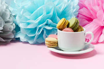 Colorful macarons in the cup on pink background with copy space