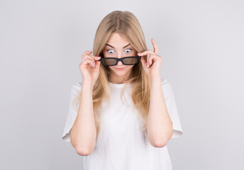 Young woman with glasses is very surprised looking down and lowering her glasses. Surprise and...