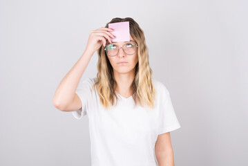 Photo of amazing blonde woman looking up empty space with deep thinking, with sticker on her forehead, isolated on gray background