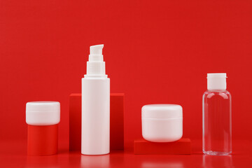 Set of face or body creams and beauty products for skin care with geometric props against red background. Concept of beauty routine and daily skin care or anti aging skin treatment