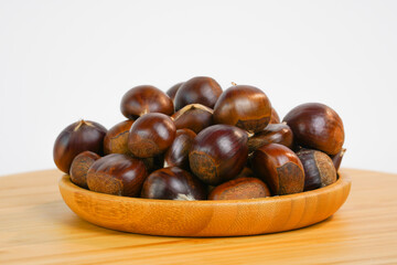 Chestnuts in a bowl.  Chestnuts isolated  on white background. Nuts in a wooden bowl. Studio photo. Product for sale. Copy space.