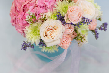 Flower arrangement in a hat box. On a light background. Bouquet of light, delicate flowers.