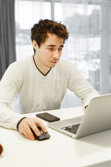 A man working on a laptop at home at bright kitchen