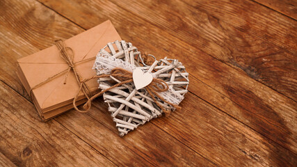 A lot of envelopes from kraft paper tied with string with hand made white heart on a wooden background