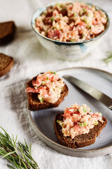 Homemade French dish rilette or pate. Two toasts salmon rillettes (pate) on rye bread on plate over beige linen tablecloth. Selective focus