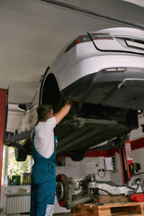 Technician working under lifted car on service station