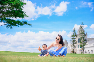 Fototapeta premium Mother and baby boy playing on the grass summer background with mum and child