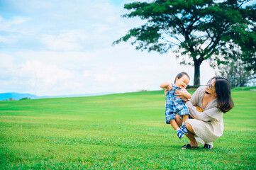 Mother and baby boy playing on the grass summer background with mum and child