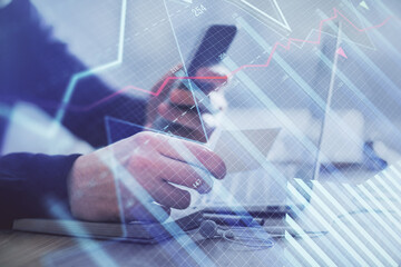 Double exposure of man's hands holding and using a phone and financial graph drawing. Analysis concept.
