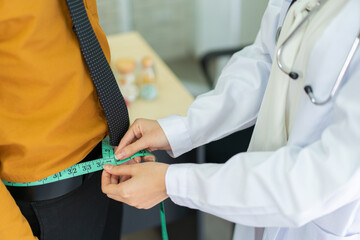 Unrecognizable doctor measuring obese male patient waist by using measuring tape.