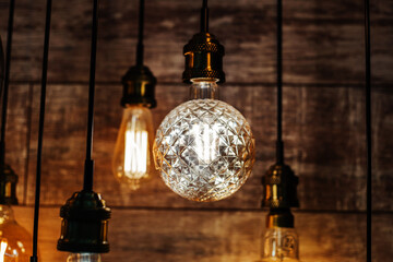 Obraz premium Retro style light bulbs hang on a wooden wall background. LED lighting equipment in a shop window