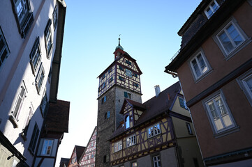 Fototapeta na wymiar Historical half-timbered houses and the Josenturm tower in the old town of Schwäbisch Hall, Germany under a clear blue sky.