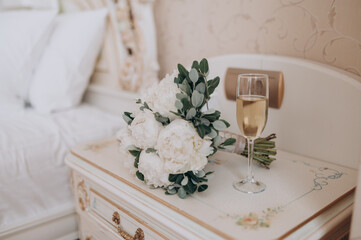 a glass of champagne is on the nightstand with a bouquet of flowers