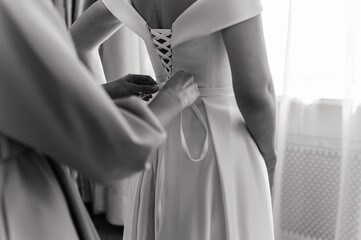 the bride in a white dress stands at the window