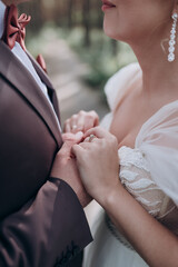 Obraz premium the bride in a beautiful white dress with a long veil and the groom holding hands