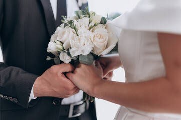 the groom in a suit and the bride with a bouquet of flowers are standing next to each other