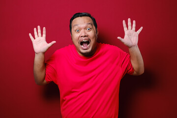 Fototapeta premium Asian man feels shock and surprise with overly face expression over red background