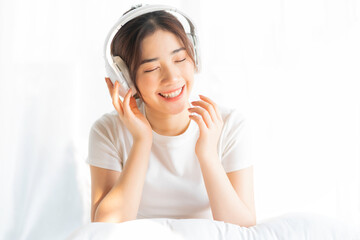 Young girl sitting in bed listening to entertaining music