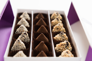 In the box are rows of different chocolates. A gift or greeting. Festive dessert.