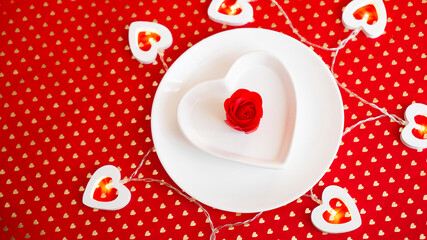 Place setting in red and white - for Valentine or other event. White plate in the shape of a heart with a decor of roses on a red background