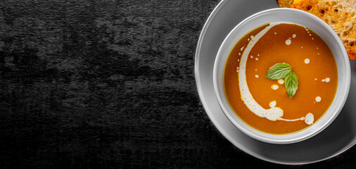 Pumpkin soup in bowl on Dark grey black slate background