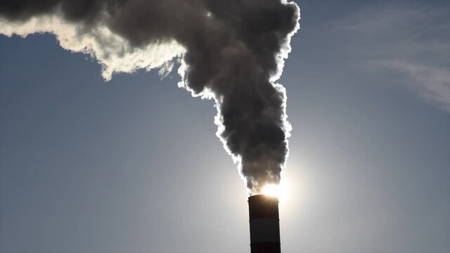 Dark hot smoke coming out of an industrial chimney of a chemical plant. Air pollution and global warming	