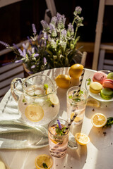 a small table in an outdoor cafe with lemonade, pasta and lavender