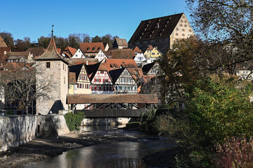 Fototapeta na wymiar Cityscape of Schwäbisch Hall, Germany with its colorful half-timbered houses, a stone city wall and a wooden bridge that is leading over a river.