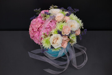 Floral arrangement of delicate peonies and other flowers, on a dark background.