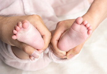 Obraz na płótnie Canvas 赤ちゃんの足を握る両親の手（0歳、生後6カ月、日本人、女の子、顔無し）
