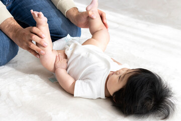 Obraz na płótnie Canvas 赤ちゃんの紙おむつ交換する父親(0歳、生後6ヶ月、女の子、日本人)