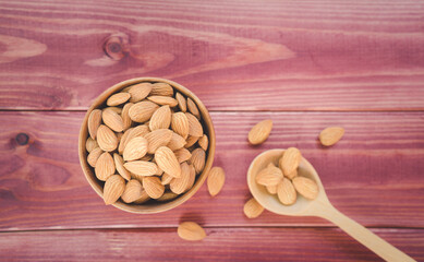 Almonds in brown wooden bowl with wooden spoon on wooden table background.Healthy food Concept.