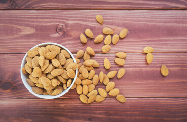 Almonds raw peeled in white porcelain bowl on wooden table background.Healthy food Concept.