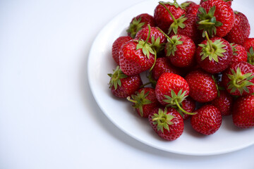 Strawberries on white plate. Freshly picked strawberry. Organic berries on white background. Village garden harvest.