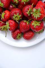 Strawberries on white plate. Freshly picked strawberry. Organic berries on white background. Village garden harvest.