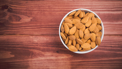 Almonds raw peeled in white porcelain bowl on wooden table background.Healthy food Concept.