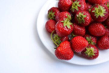 Strawberries on white plate. Freshly picked strawberry. Organic berries on white background. Village garden harvest.