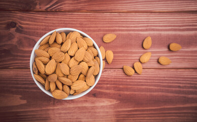 Almonds raw peeled in white porcelain bowl on wooden table background.Healthy food Concept.