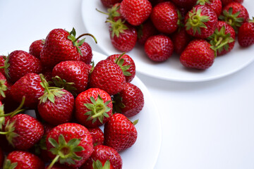 Strawberries on white plate. Freshly picked strawberry. Organic berries on white background. Village garden harvest.